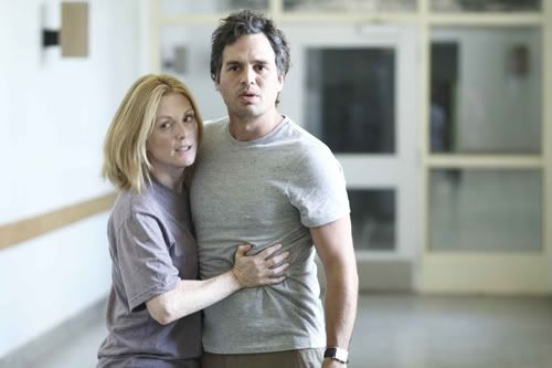 Julianne Moore and  Marc Ruffalo in the hallway of some kind of hospital. They are both wearing gray t-shirts. Ruffalo looks off into the distance and Moore clutches his stomach, looking wary.